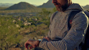 man checking watch outside at sunset