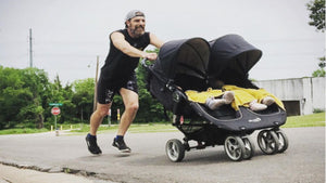 dad pushing stroller with two kids while jogging