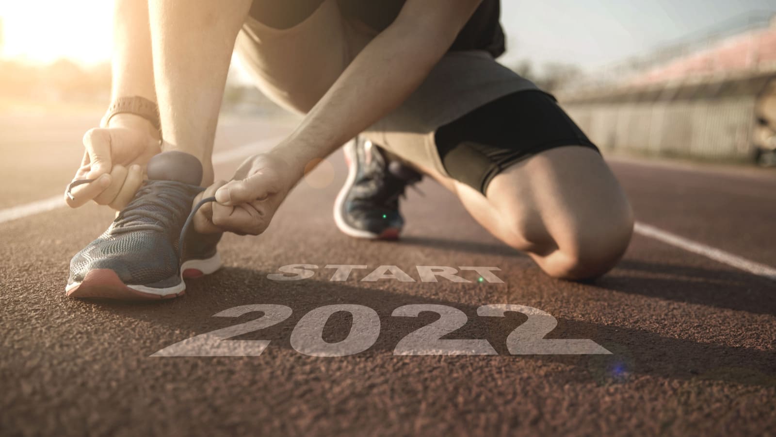 person at starting line tying running shoe